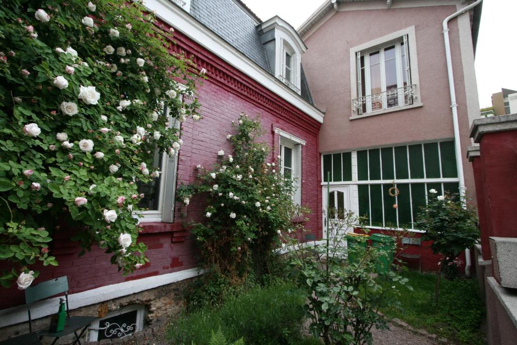 una casa rosa con rosas a un lado. en La Maison Rouge en París