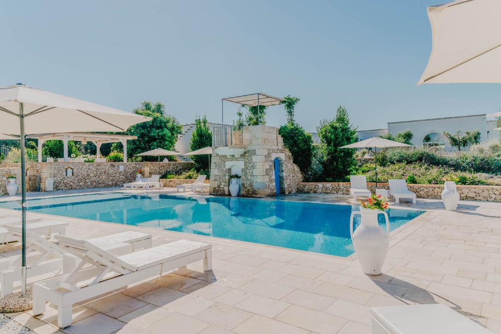 uma piscina com cadeiras e guarda-sóis em frente a uma casa em Masseria Muntibianchi AgriResort Restaurant & SPA em Otranto