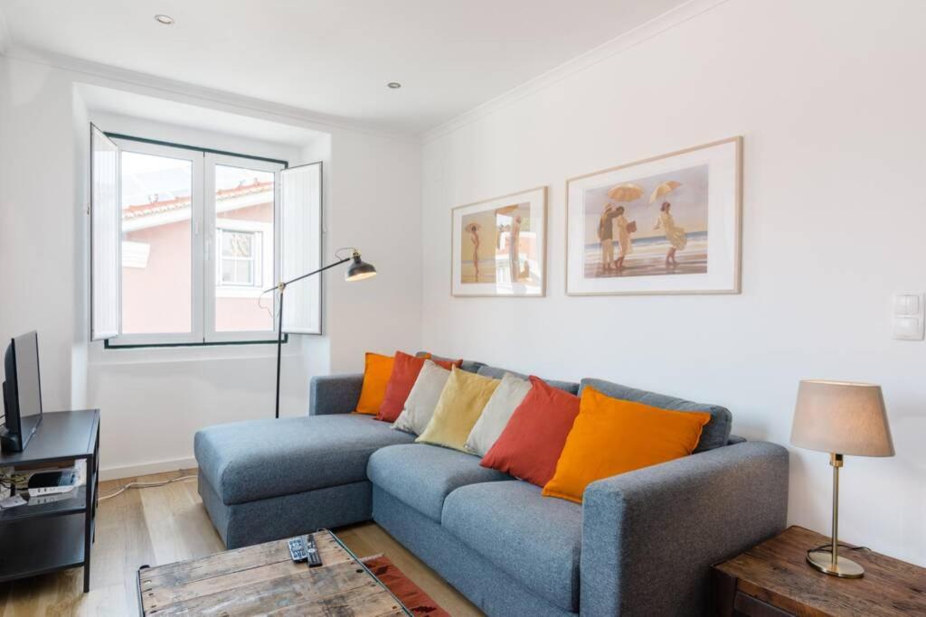 a living room with a blue couch with colorful pillows at Beautiful Apartment with View of the Tagus River in Lisbon