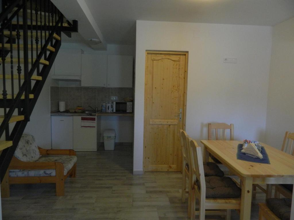 a kitchen and a dining room with a table and a staircase at Família-Pelso apartmanház in Zamárdi