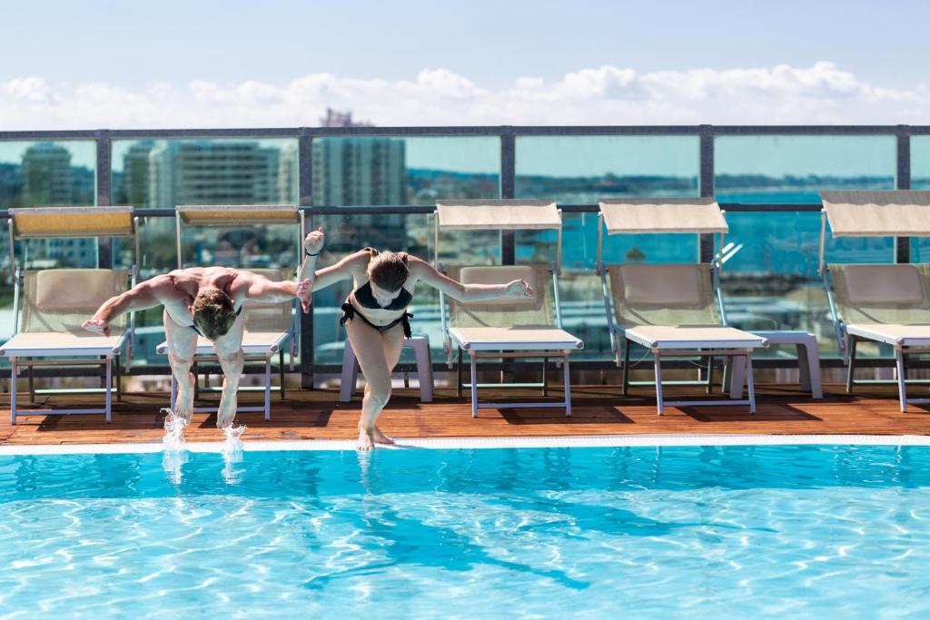 duas pessoas a brincar numa piscina no telhado em Hotel Universal em Cattolica