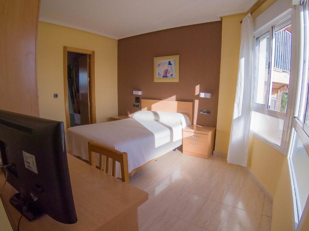 a hotel room with a bed and a television at Hostal Meseguer in El Altet