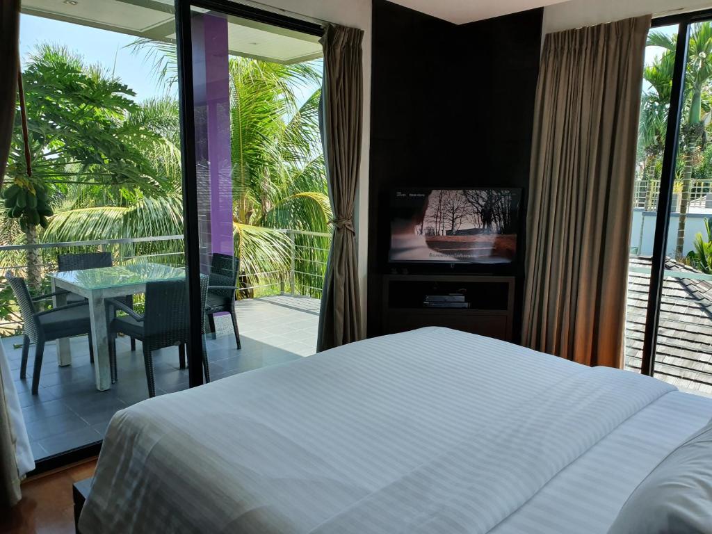 een slaapkamer met een bed en een televisie en een tafel bij Eden Villa Phuket in Bang Tao Beach