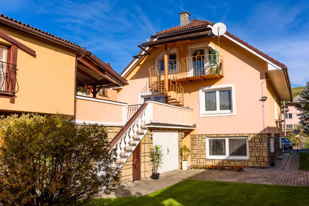 a house with a balcony and a yard at Apartman Elegant in Bešeňová