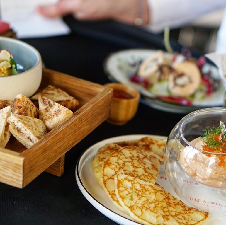 a table with plates of food and a tray of bread at Hôtel le XIX in Béziers