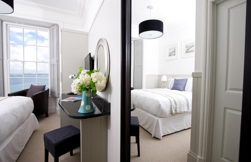 a bedroom with a bed and a desk with a mirror at Henry's, 27 The Terrace in St Ives