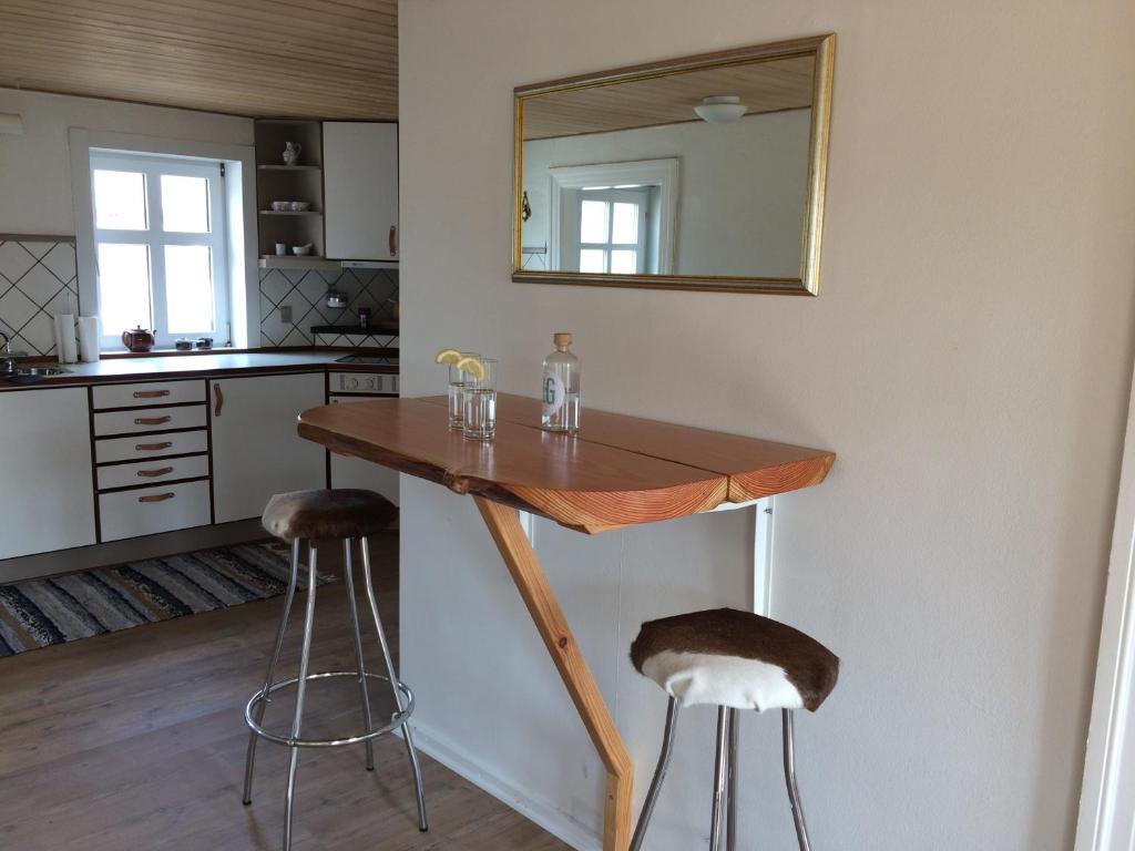 a kitchen with a wooden table and two bar stools at Sejtræk Apartments in Tversted