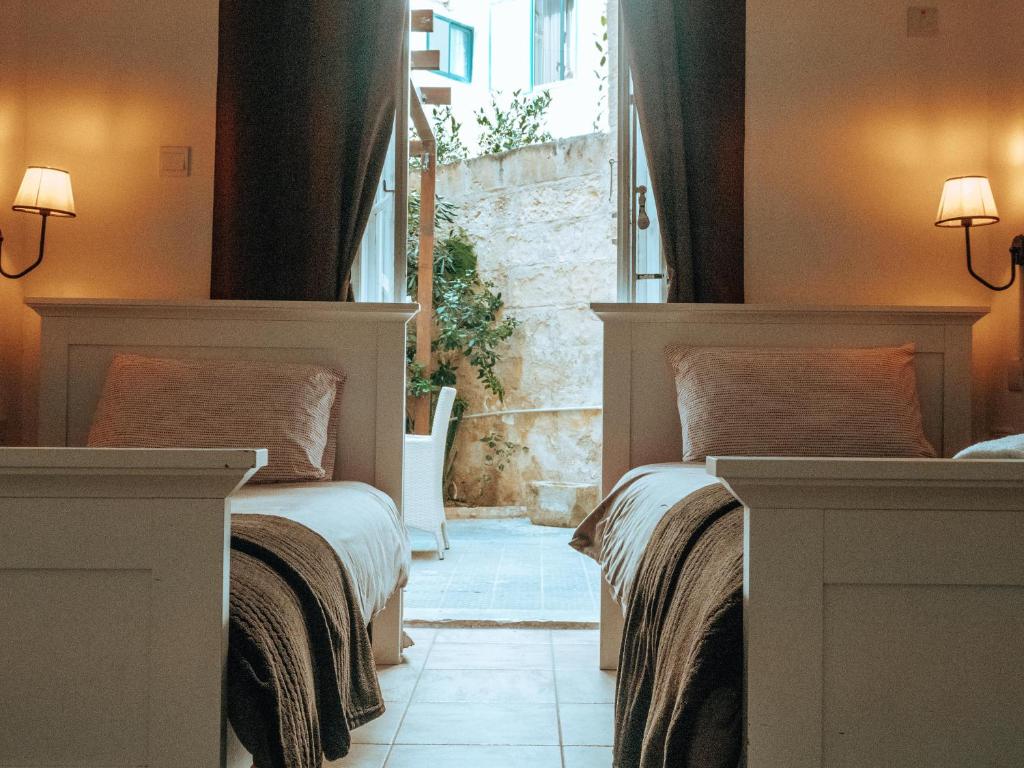 two beds in a room with a window at The Maltese Sun in Sliema