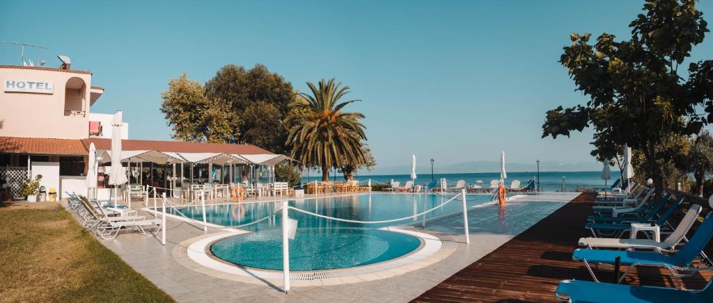 a swimming pool with chairs and the ocean in the background at Vournelis Hotel in Limenas