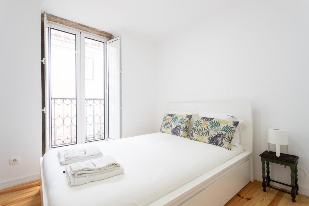 un letto bianco in una stanza con finestra di FLH Mouraria Charming Flat II a Lisbona
