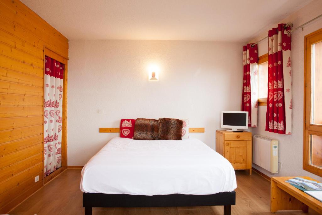 a bedroom with a white bed and a television at Le Floralp in Combloux