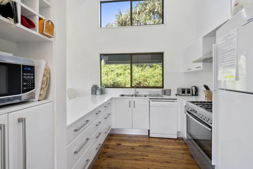 a white kitchen with white appliances and a window at Beachtime in Point Lookout