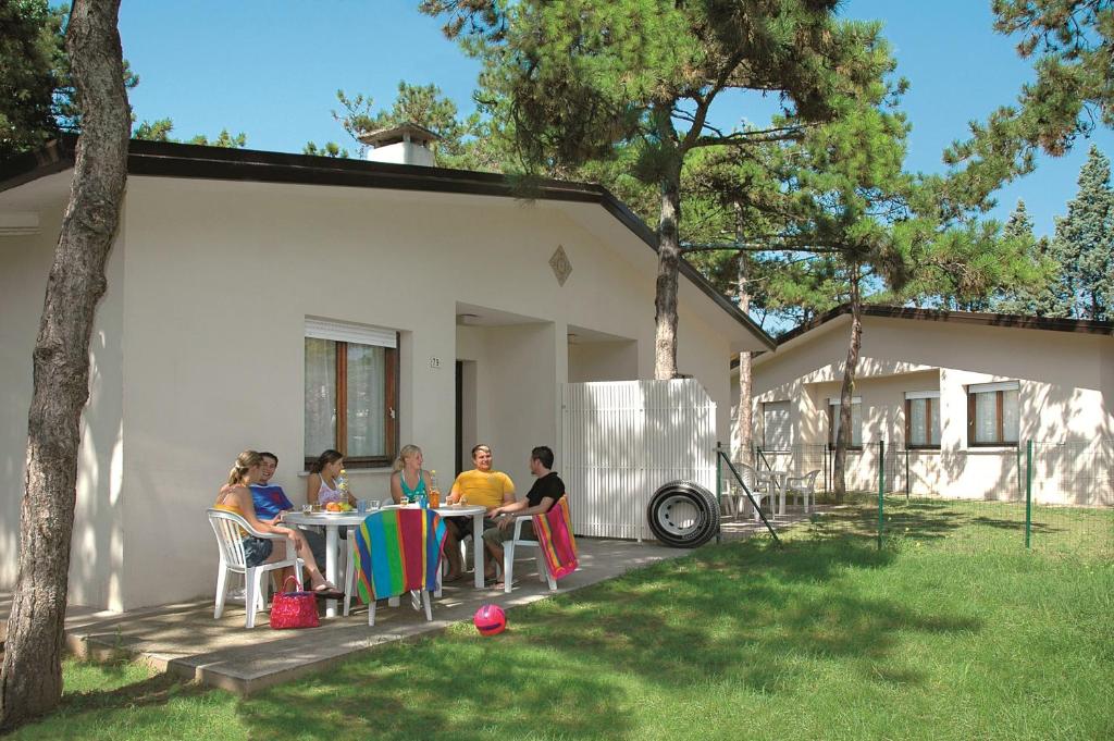 un gruppo di persone seduti a un tavolo in un cortile di Villaggio Le Palme a Lignano Sabbiadoro