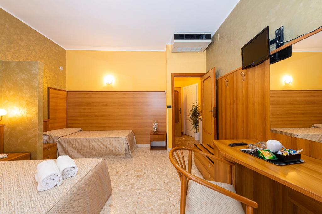 a hotel room with two beds and a desk at La Lanterna in Silvi Marina