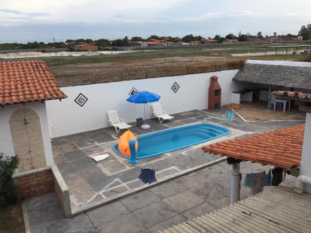 a pool with two chairs and an umbrella on a patio at Casa de Dona Diana in Barreirinhas