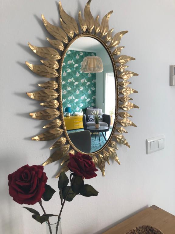 un espejo en una pared con un jarrón con rosas en El Balcón de Rosita en Morche