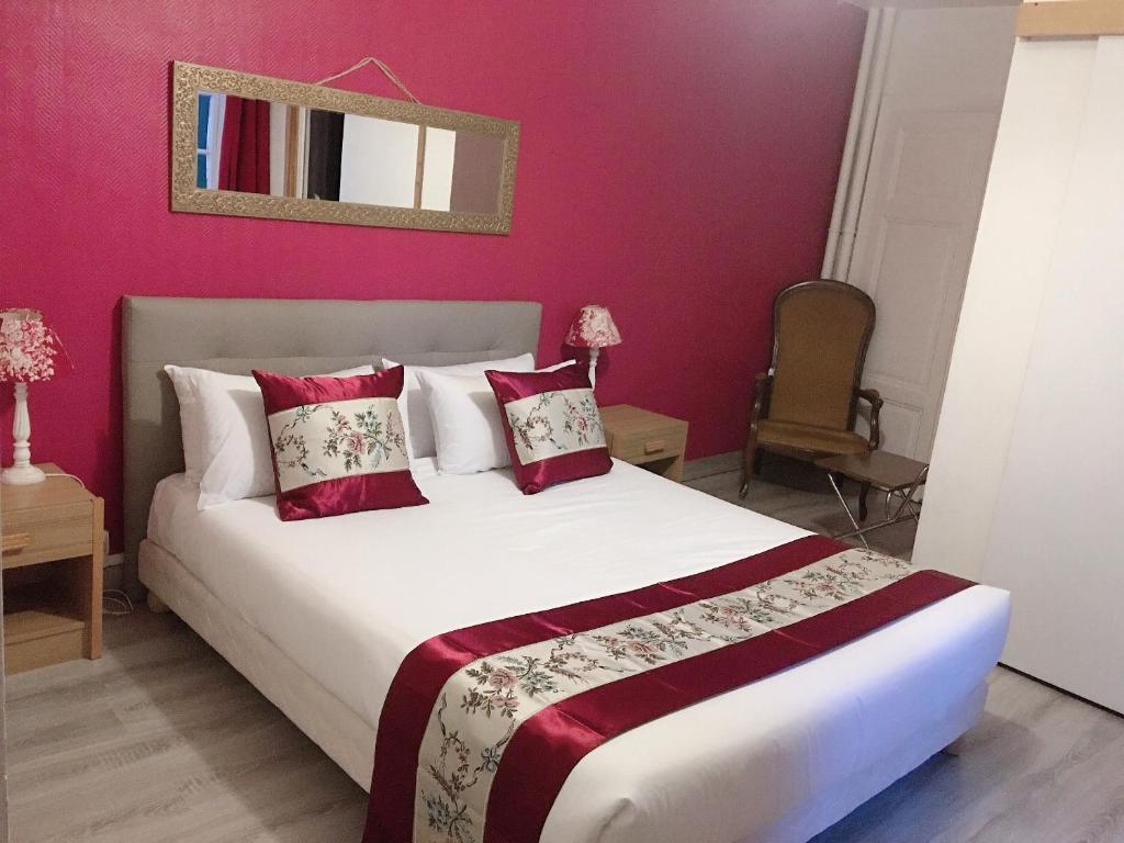ボンソンにあるHOTEL HOSTELLERIE DES VOYAGEURSのピンクの壁のベッドルーム1室(大型ベッド1台付)