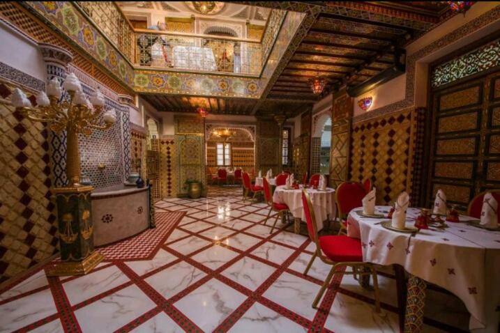 un ristorante con tavoli e sedie in una stanza di PALAIS LARAICHI Riad la porte bleue suites a Fes