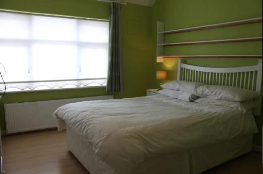 1 dormitorio con 1 cama blanca y 2 ventanas en killowen, en Dublín