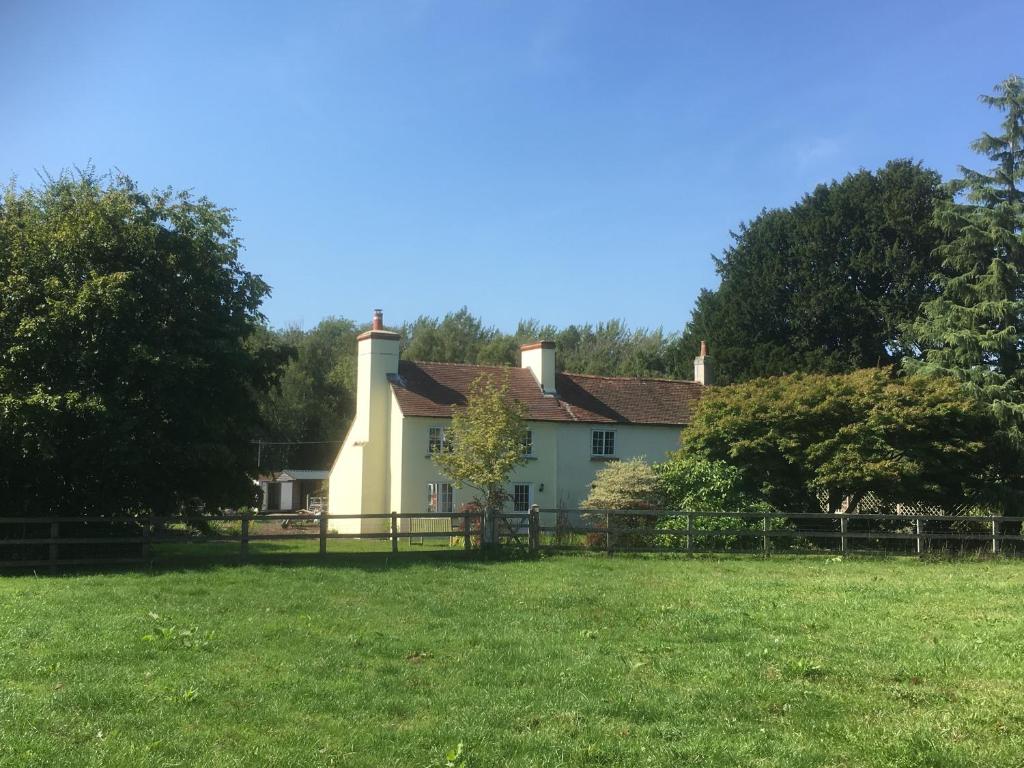 una casa blanca con una valla en un campo en Woodlands Cottage Farm, en Wickham