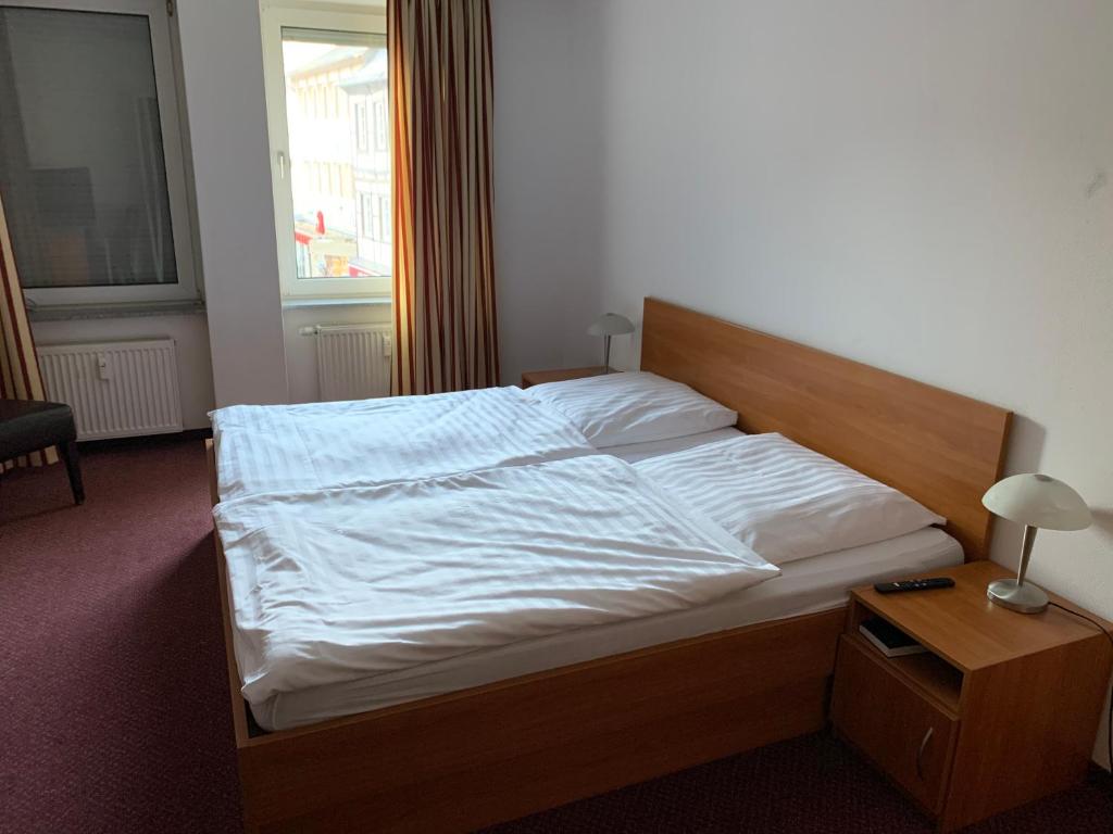 a bedroom with a bed with white sheets and a window at Pension Hannes in Kirn