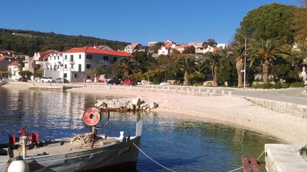 a boat is docked in the water next to a beach at Apartments and rooms Rest - close to the sea &amp; comfortable in Sumartin