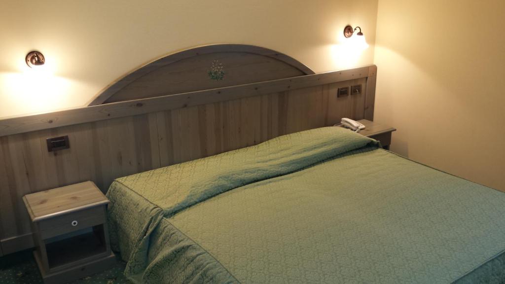 sypialnia z łóżkiem i 2 lampkami na ścianie w obiekcie Hotel Pesek w mieście San Dorligo della Valle