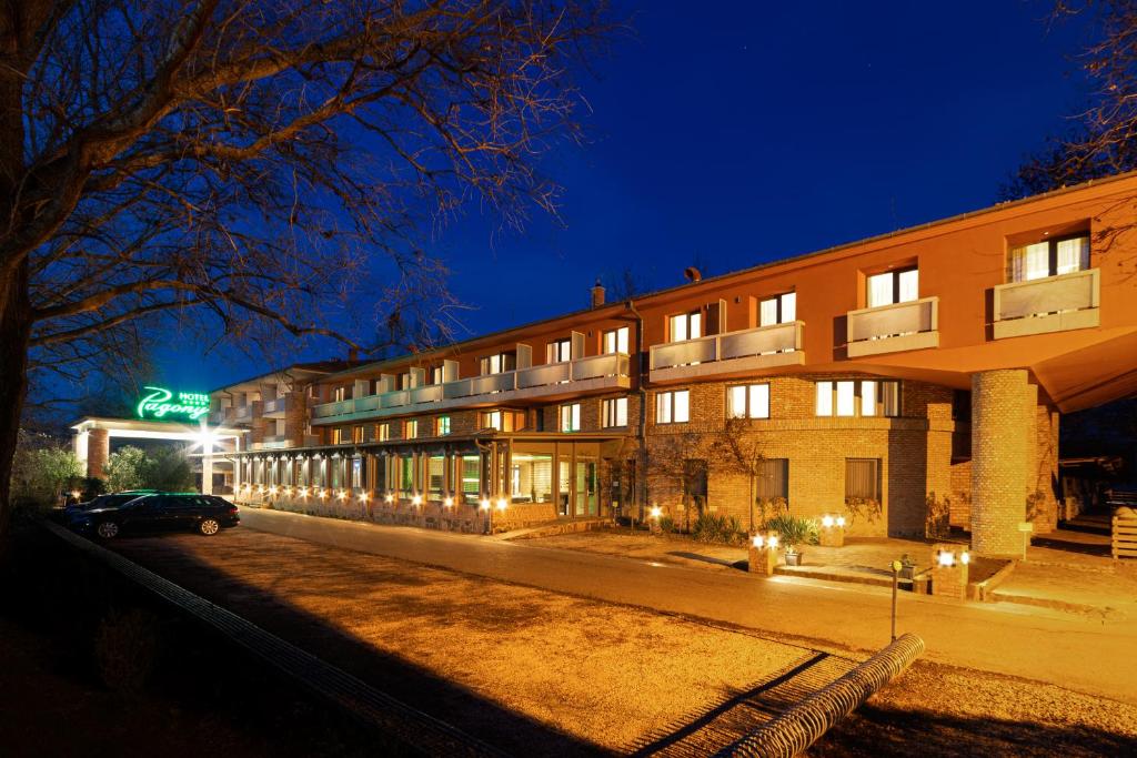 um edifício com um carro estacionado em frente dele à noite em Hotel Pagony Wellness em Nyíregyháza