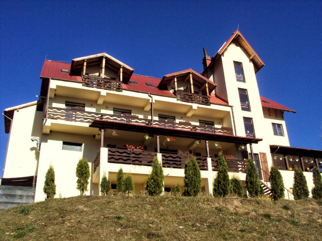 a large white building on top of a hill at Pensiunea Lostrita in Buhalniţa