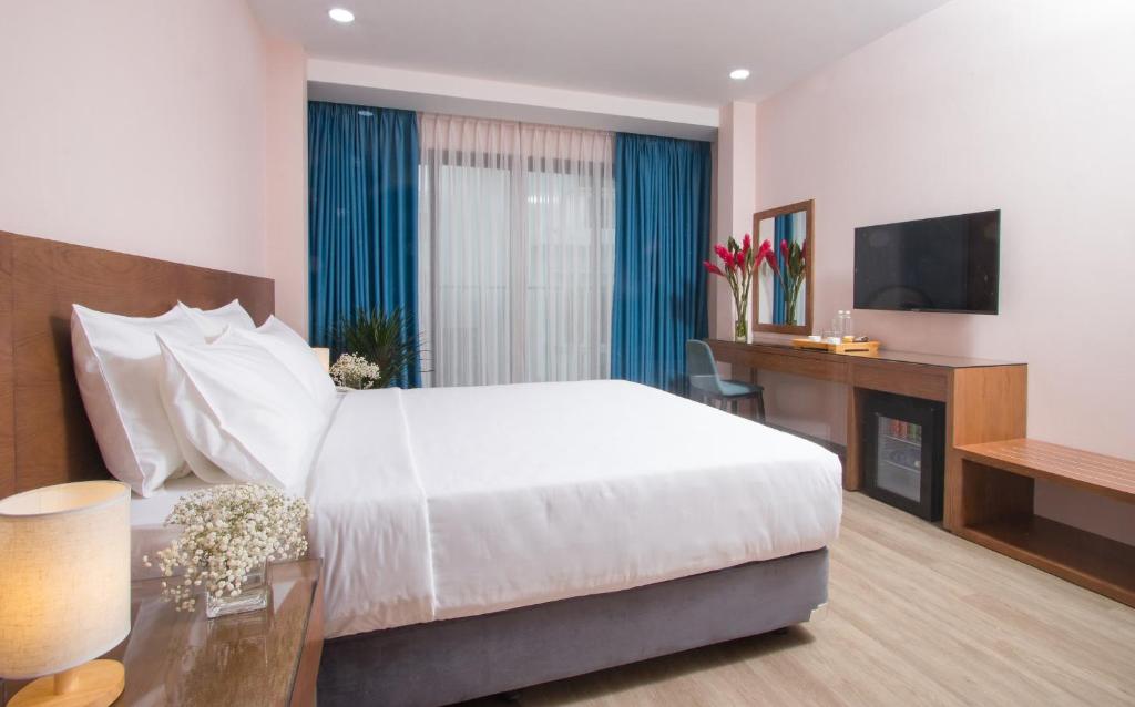 een slaapkamer met een bed, een bureau en een televisie bij PIANO HOTEL in Ho Chi Minh-stad