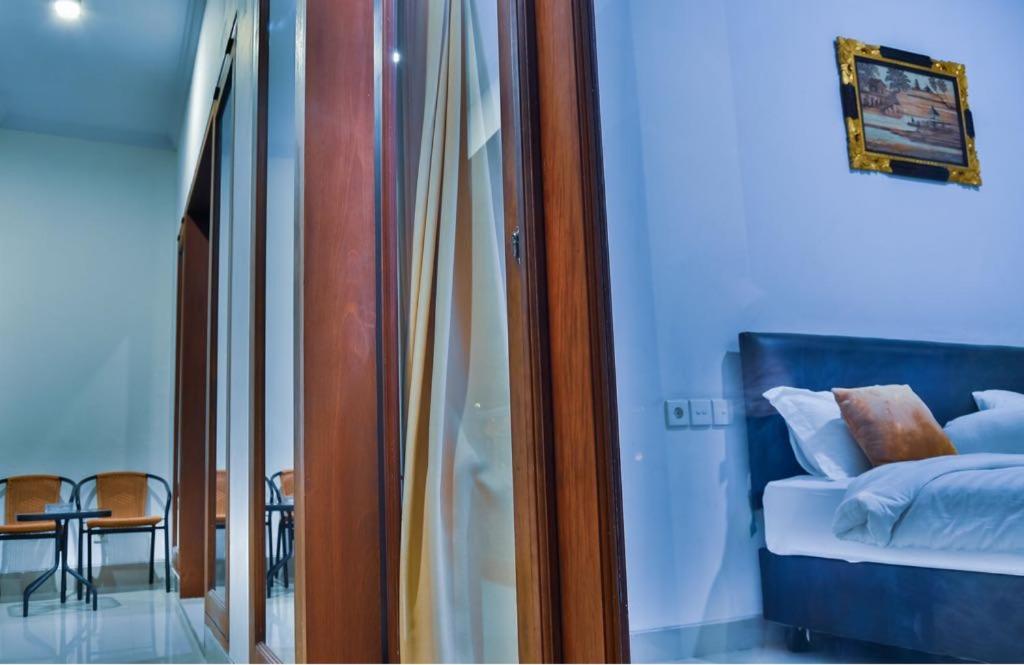 1 dormitorio con cama, mesa y ventana de cristal en Degung de brata Family villas, en Legian