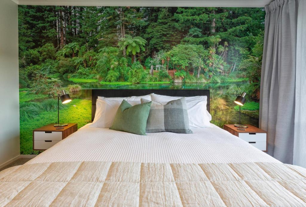 a bedroom with a large bed with a forest mural at Parkside Boutique Lodge in Rotorua