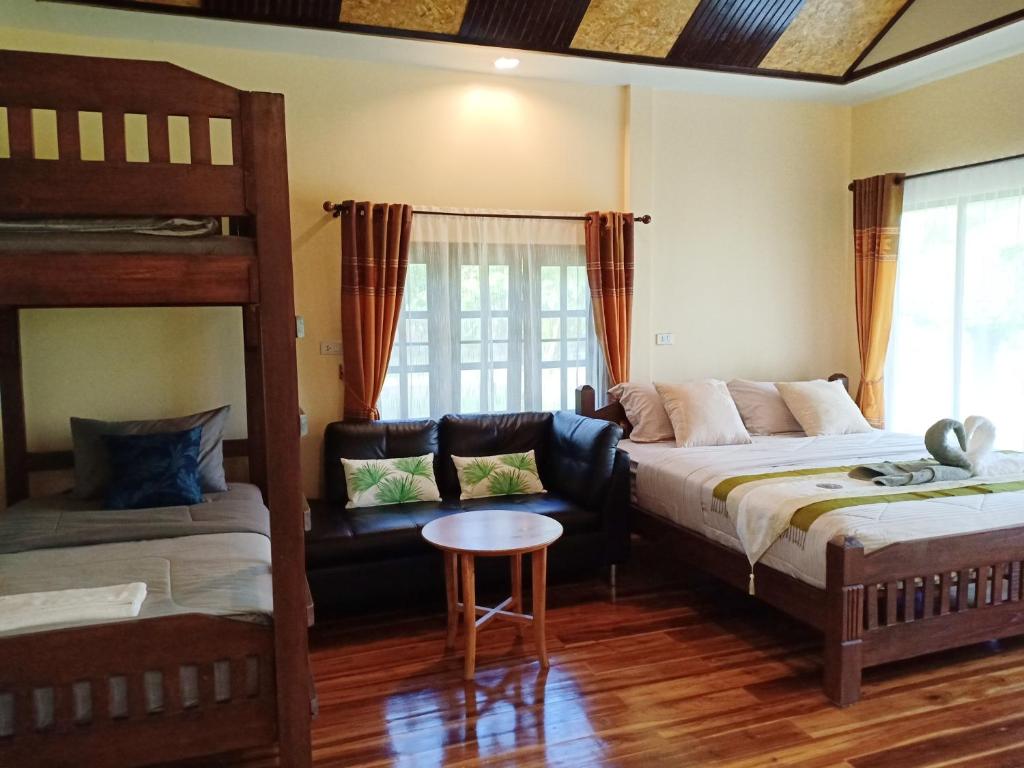a bedroom with two bunk beds and a couch at Rai Lung Tui Homestay in Prachuap Khiri Khan