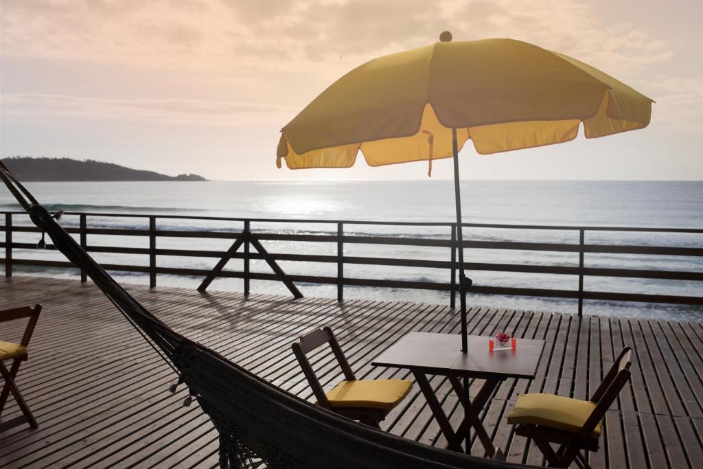 uma mesa e cadeiras com um guarda-sol e o oceano em Hibisco Guest House em Florianópolis