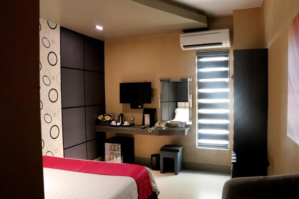 a bedroom with a bed and a window and a desk at Eloisa Royal Suites in Mactan