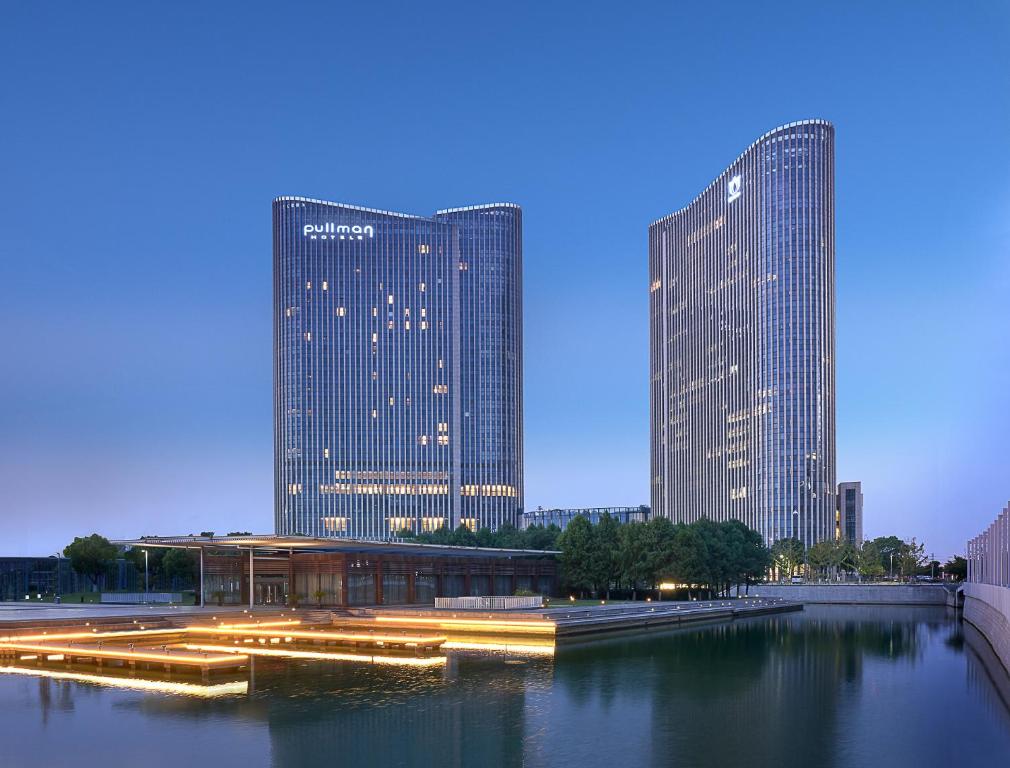 two tall skyscrapers in a city at night at Pullman Wuxi New Lake in Wuxi