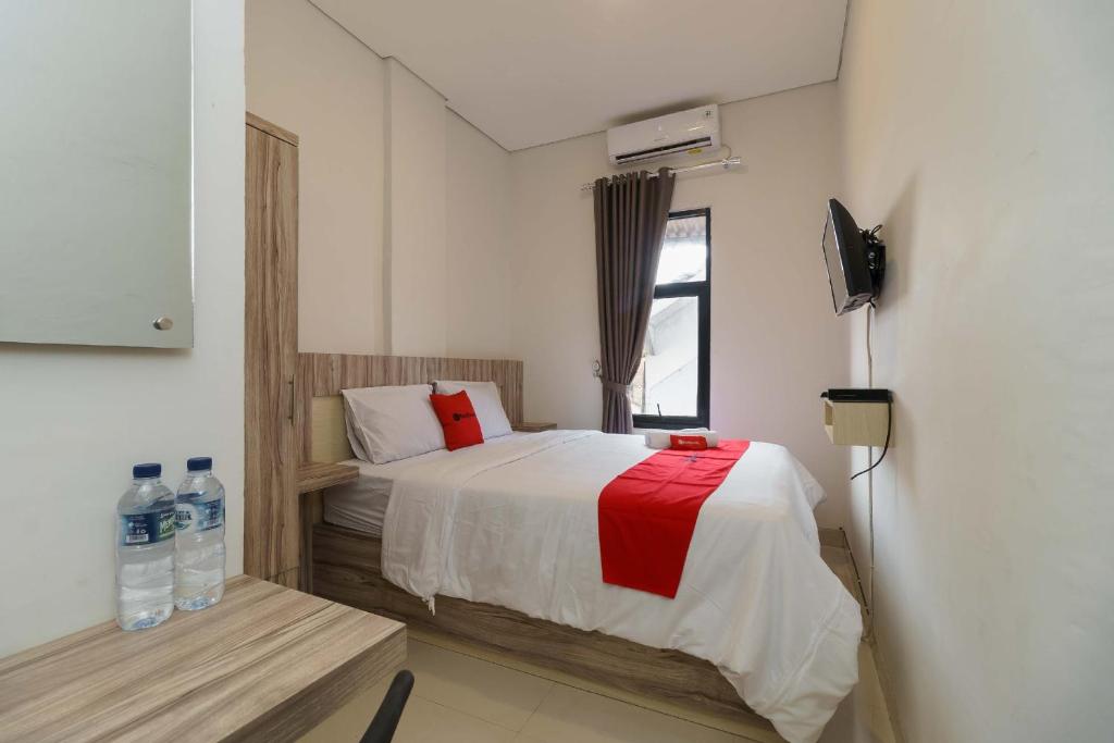 um pequeno quarto com uma cama e uma janela em RedDoorz Syariah near RSUD Siti Fatimah Palembang em Palimbão