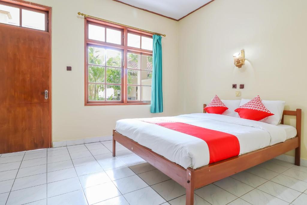 a bedroom with a large bed with red and white pillows at OYO 1654 Maha Bharata Kuta Inn in Legian