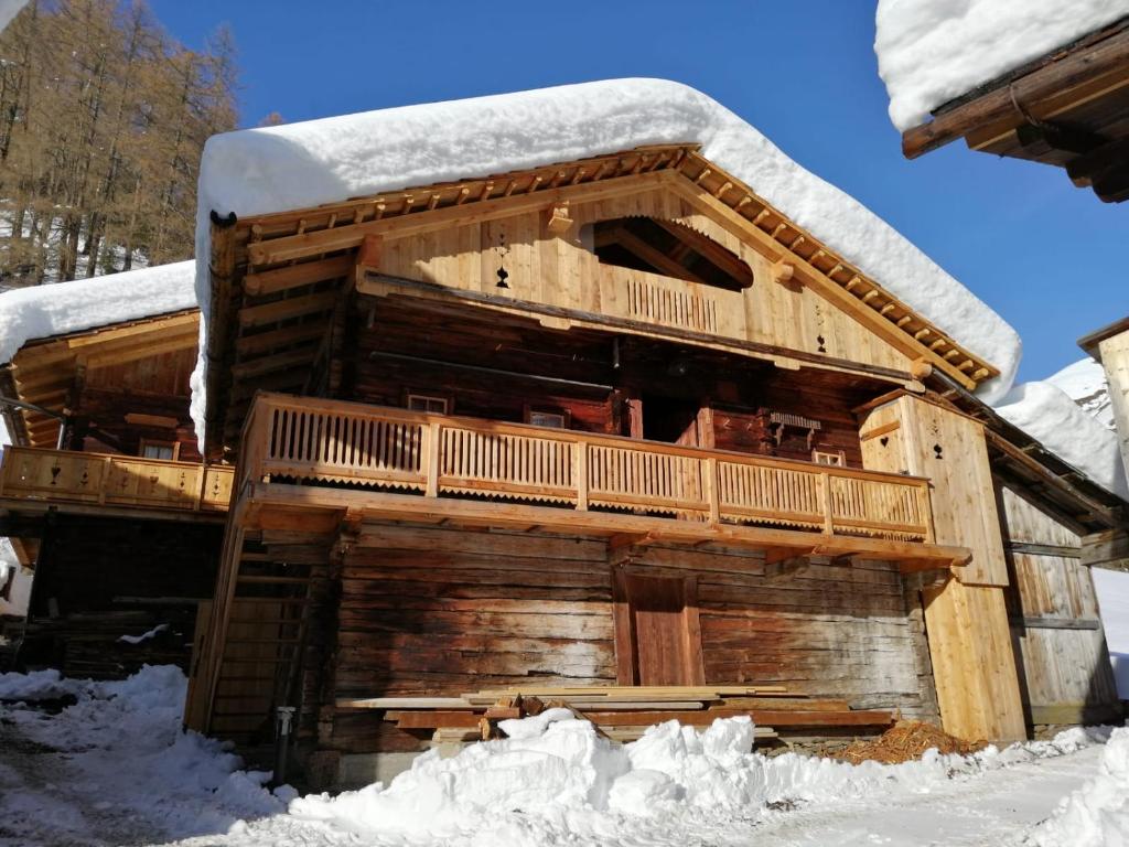 eine Blockhütte mit Schnee auf dem Dach in der Unterkunft Almhütte Senfter in Innervillgraten