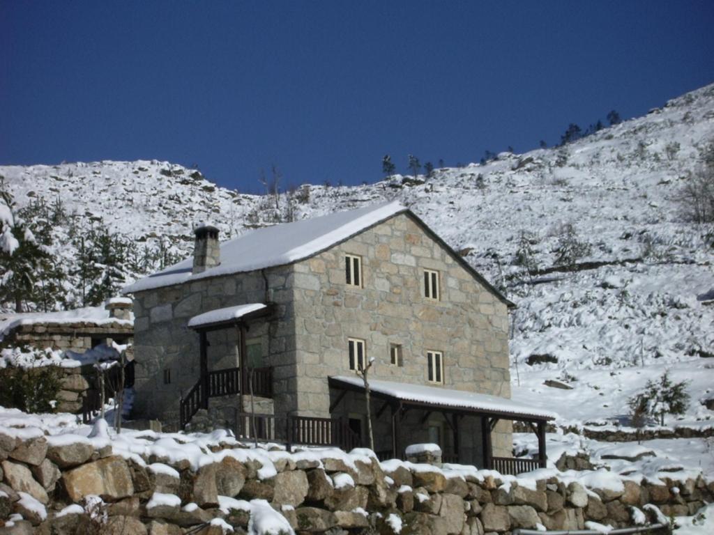 a stone building with snow on top of a mountain at Quinta De Cabrum in Alvoco da Serra