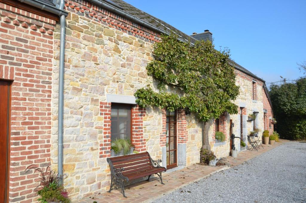 eine Bank, die vor einem Backsteingebäude sitzt in der Unterkunft B&B Aux Gaietés de la Sabotière in Seloignes