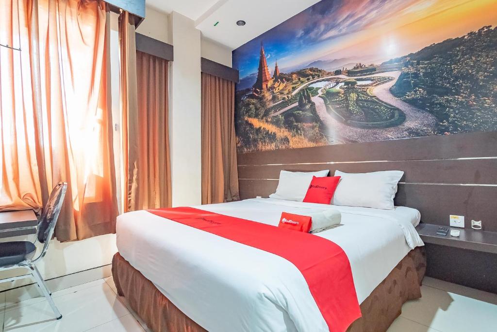 una camera da letto con un grande letto e un dipinto sul muro di RedDoorz near Stadion Sanaman Mantikei a Palangkaraya