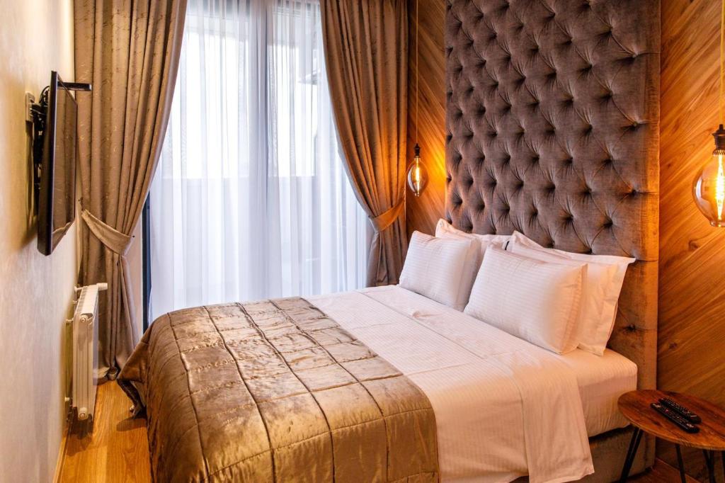 a bedroom with a large bed with a large window at Dali Apartments Pupin Palace in Novi Sad