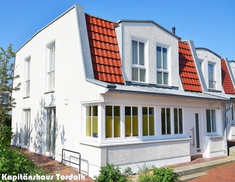 une maison blanche avec un toit orange dans l'établissement Kapitänshaus Tordalk mit 3 Schlafzimmern, à Norderney