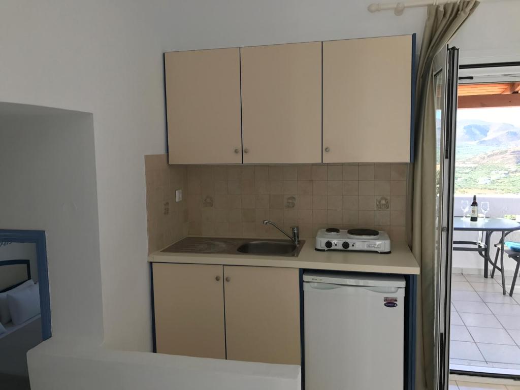 a kitchen with white cabinets and a sink at Castri Village Hotel in Palekastron