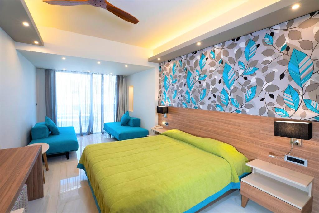 a bedroom with a green bed and blue chairs at Atrion Resort Hotel in Agia Marina Nea Kydonias