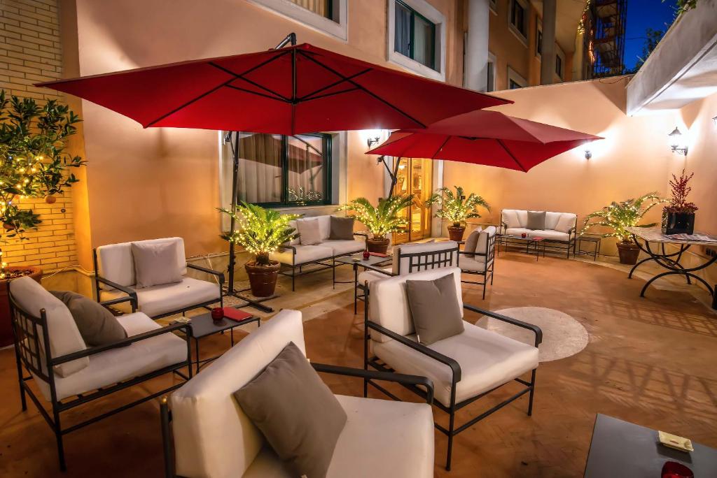 een patio met stoelen, tafels en rode parasols bij River Chateau Hotel in Rome