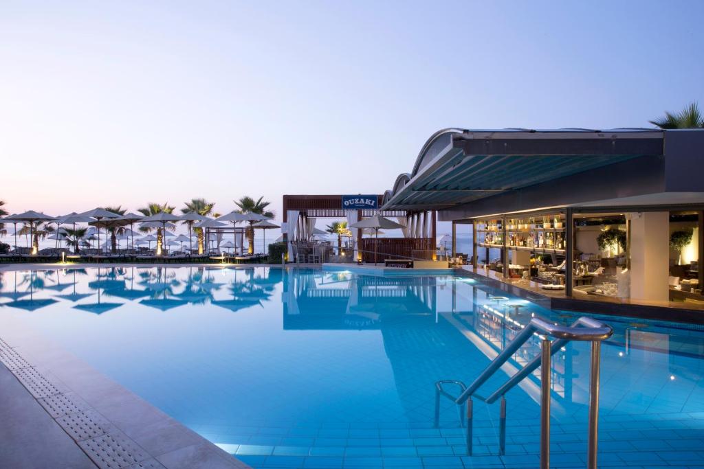 a pool at a hotel with blue water and umbrellas at Thalassa Beach Resort & Spa (Adults Only) in Agia Marina Nea Kydonias