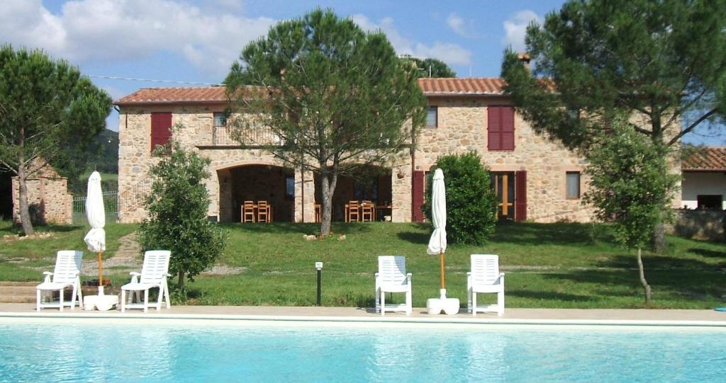 - une piscine avec des chaises et des parasols en face d'une maison dans l'établissement Casetta Francini, à Civitella Marittima