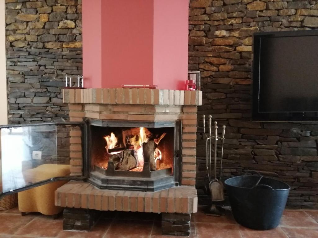 a fireplace in a living room with a tv at Mirador del Duque in Güéjar-Sierra